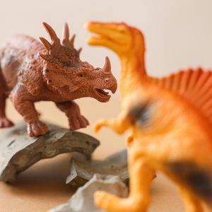 Close-up of toy dinosaurs in a playful encounter on rocky terrain.